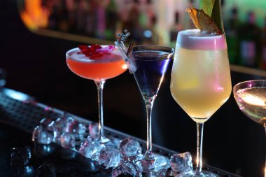 Barda farklı taze alkollü kokteyller ve buz küpleri var.