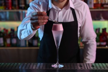 Barmen bardaki tezgahta taze alkollü kokteyl ile süslüyor.