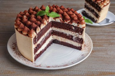 Nefis tiramisu keki ve ahşap masa üzerinde nane yaprakları.