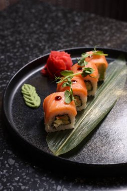 Somonlu lezzetli suşi dürümleri karanlık masada, yakın plan.