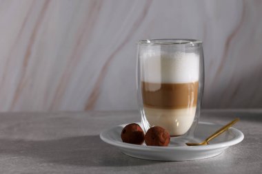 Camla kaplanmış Aromatik latte macchiato ve siyah arka planda gri masada çikolata şekeri. Metin için boşluk