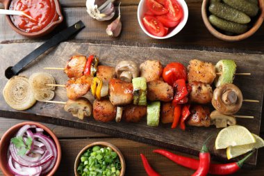 Lezzetli şiş kebap, mantar, domates ve kabak, ahşap masada servis edilir, düz uzanır.