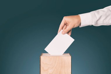 Adam oylarını oy sandığına koyuyor. Renkli arka planda, yakın planda. Metin için boşluk