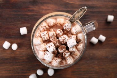 Bir fincan aromatik sıcak çikolata, marşmelov ve kakao tozu, ahşap masa, üst manzara.