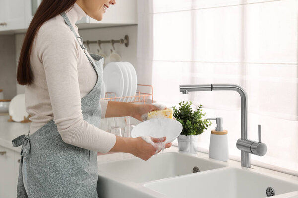 Woman washing bowl at sink in kitchen, closeup
