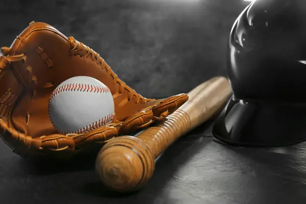 Baseball glove, bat, ball and batting helmet on black table, closeup