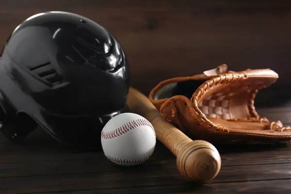 Baseball glove, bat, ball and batting helmet on wooden table