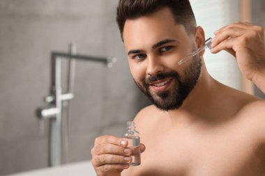 Banyoda yüzüne kozmetik serumu süren yakışıklı bir adam. Metin için boşluk