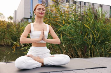 Güzel bir genç kadın yoga minderinde Padmasana egzersizi yapıyor. Lotus pozu