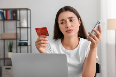 Kredi kartı, akıllı telefon ve dizüstü bilgisayarla kafası karışmış bir kadın. Dikkatli ol, sahtekar.
