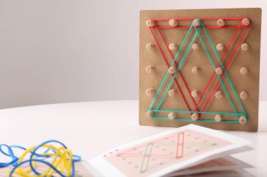 Kauçuk bantlı tahta jeokart ve talimatlar beyaz masada, mesaj için yer var. Motor beceriler geliştirme