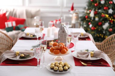 İçinde mandalina, şeker ve bulaşık takımı olan bir Noel masası.