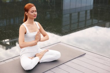 Güzel genç bir kadın yoga minderinde Padmasana egzersizi yapıyor, mesaj için yer var. Lotus pozu