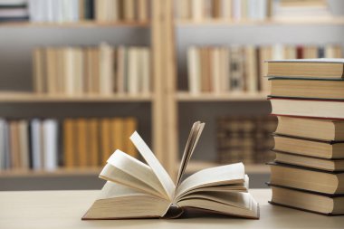 Kütüphanedeki ahşap masada bir sürü kitap var.