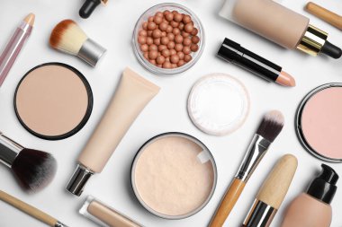Beyaz arka planda yüz pudraları ve diğer makyaj ürünleri, düz yatıyordu