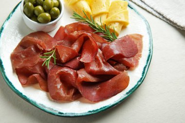 Nefis bresaola, peynir, zeytin ve biberiye açık dokulu masa.