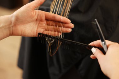Güzellik salonunda kızın saçını kesen profesyonel kuaför, yakın plan.