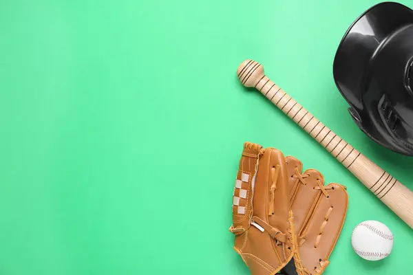Baseball glove, bat, ball and batting helmet on green background, flat lay. Space for text
