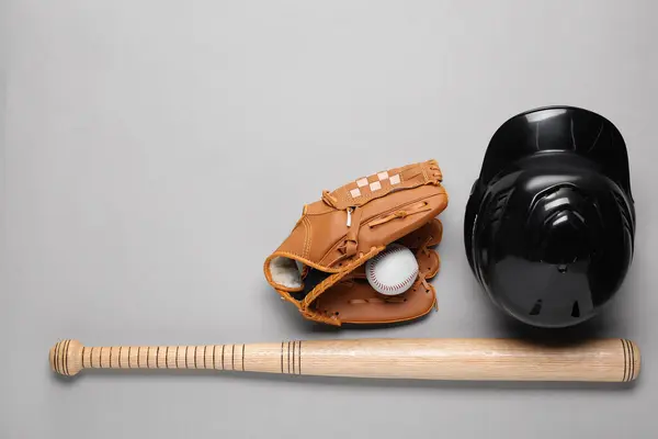 Baseball glove, bat, ball and batting helmet on light grey background, flat lay. Space for text