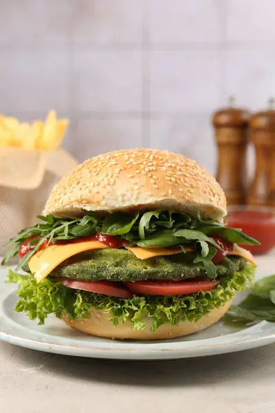 Tasty vegetarian burger with spinach cutlet, cheese and vegetables served on white table, closeup
