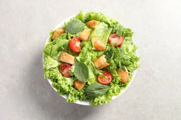 Delicious salad with chicken, cherry tomato and spinach on light grey table, top view
