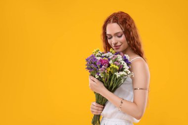 Turuncu arka planda bir buket renkli çiçekli güzel hippi kadın, mesaj için yer var.