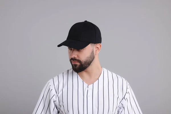Man in stylish black baseball cap on light grey background