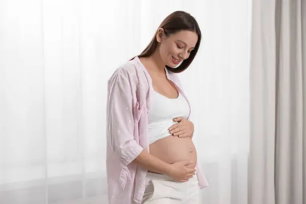 Vacker Gravid Kvinna Rosa Skjorta Nära Fönstret Inomhus — Stockfoto