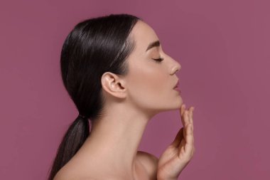 Koyu pembe arka planda mükemmel makyajlı güzel bir genç kadının portresi.