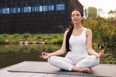 Güzel genç bir kadın yoga minderinde Padmasana egzersizi yapıyor. Lotus pozu