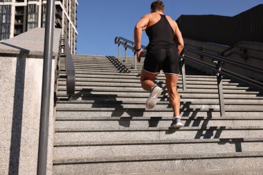Güneşli bir günde merdivenlerden koşarak çıkan bir adam.