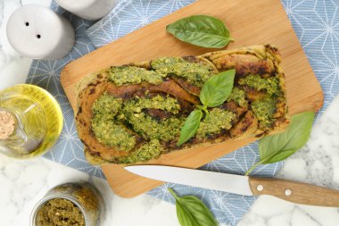 Taze pişmiş pesto ekmeği, fesleğen ve bıçakla bembeyaz mermer masada, düz yatıyordu.