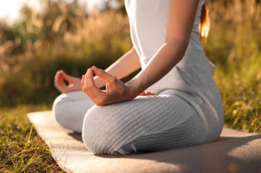 Dışarıdaki yoga minderinde Padmasana egzersizi yapan kadın, yakın plan. Lotus pozu