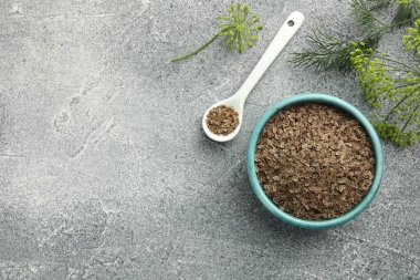 Bir kase kuru tohum, kaşık ve taze dereotu gri masada, düz yerde. Metin için boşluk