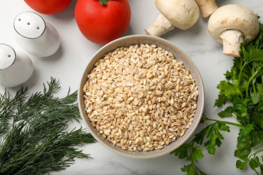 Kâse içinde kuru inci arpa ve beyaz mermer masa üzerinde ürünler, düz yatıyordu