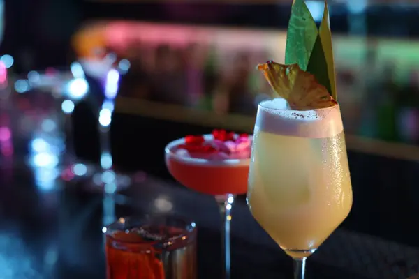 Different fresh alcoholic cocktails on blurred background, closeup. Space for text