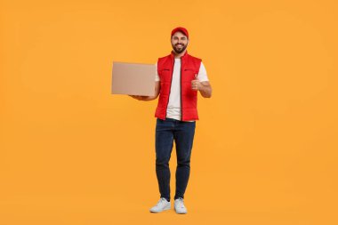 Turuncu arka planda parşömeni olan mutlu genç kurye.