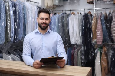 Kuru temizleme servisi. Kapalı alanda pano tutan mutlu işçi.