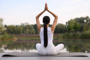 Dışarıdaki yoga minderinde Padmasana egzersizi yapan bir kadın. Lotus pozu