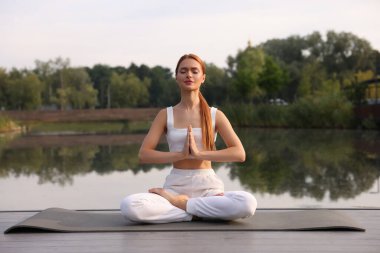 Güzel genç bir kadın yoga minderinde Padmasana egzersizi yapıyor. Lotus pozu