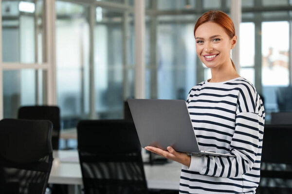 Happy woman with laptop in office, space for text