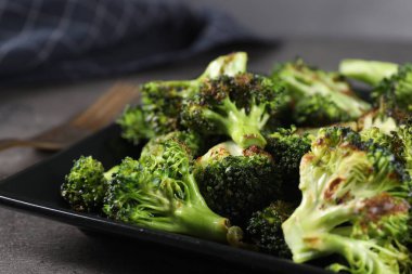 Gri masada lezzetli kızarmış brokoli, yakın plan.