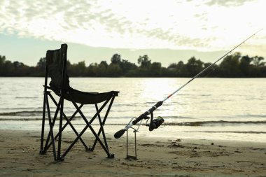 Nehir kenarındaki katlanır sandalye ve olta kamışı