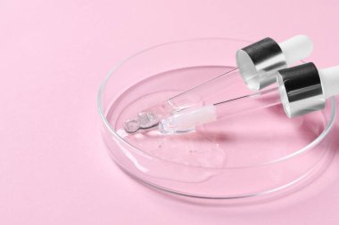 Pipetler ve petri kabı. Pembe arka planda serum örneği var. Yakın plan. Metin için boşluk