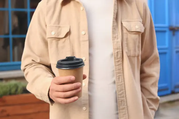Coffee to go. Man with paper cup of drink outdoors, closeup