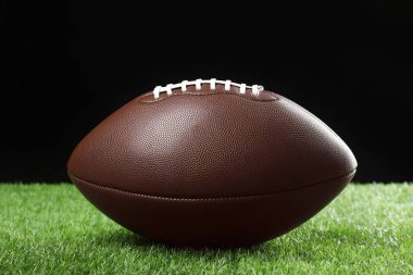 Amerikan futbol topu yeşil çimlerde siyah arka planda