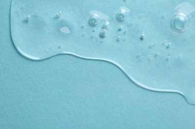 Açık mavi arkaplanda temiz kozmetik serumu, üst görüş. Metin için boşluk