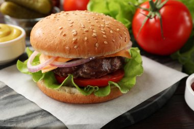 Köfteli lezzetli hamburger, peynir ve sebzeler ahşap masada, yakın plan.