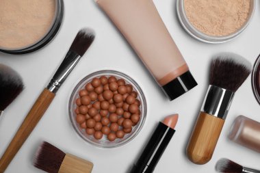 Beyaz arka planda yüz pudraları ve diğer makyaj ürünleri, düz yatıyordu