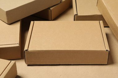 Açık kahverengi arka planda birçok kapalı karton kutu, yakın plan